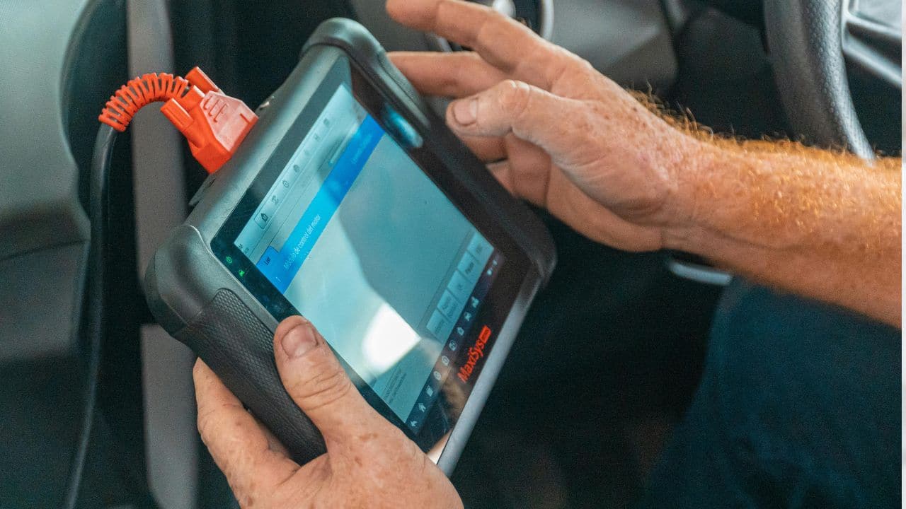 Kfz-Mechaniker bedient ein Diagnosegerät zur Prüfung und Kalibrierung von Fahrerassistenzsystemen wie Notbremsassistent und Spurhalteassistent.